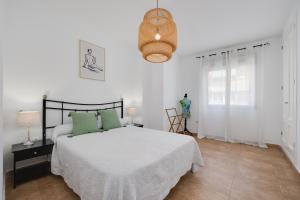 a white bedroom with a bed and a chandelier at Apartamentos Madrid in Torrevieja