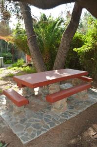 a picnic table and two benches under a tree at Helios Rooms in Quartu SantʼElena