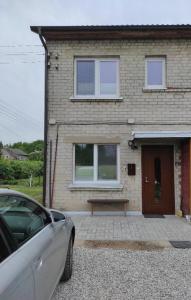 a car parked in front of a house with a bench at Apartamentai G&G in Jurbarkas