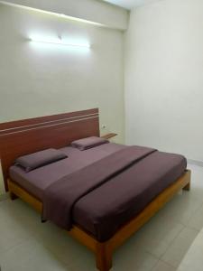 a bedroom with a large bed with a wooden headboard at mythriinn in Araku