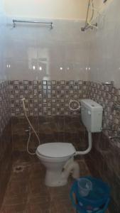 a bathroom with a toilet and a tiled wall at mythriinn in Araku