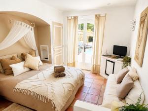 a bedroom with a bed and a couch and a tv at Le Mas d'Olivier in Le Plan-de-la-Tour
