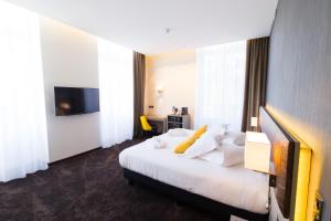 a hotel room with a bed and a television at Les Jardins du Mess in Verdun-sur-Meuse