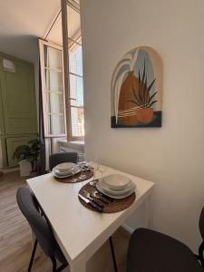 a white dining room table with plates and glasses on it at Le Cocon Bressan hyper centre & lumineux in Bourg-en-Bresse