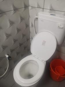 a white toilet in a bathroom with a bucket at Railviewtouristhome in Varkala