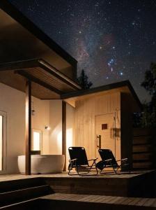 two chairs on the porch of a house at night at 軽井沢一棟貸しBBQサウナつき別荘- YURAGI - TSUKI me CHILL in Miyota