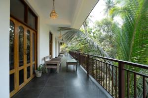 a balcony with benches and palm trees at Alpa Viram Retreat Goa in Mandrem