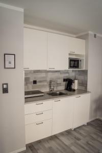 a white kitchen with a sink and a microwave at Apartment Nr 06 in Bremerhaven