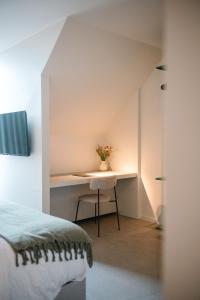 ein Schlafzimmer mit einem Schreibtisch und einer Blumenvase in der Unterkunft Between Flanders Walls in Ypern