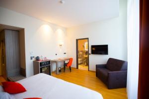 a hotel room with a bed and a couch and a desk at Les Jardins du Mess in Verdun-sur-Meuse