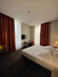a bedroom with a bed and a desk with a television at Les Jardins du Mess in Verdun-sur-Meuse