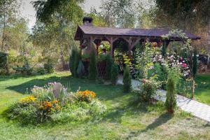 a wooden gazebo in a garden with flowers at Royal Hotel in Drăguş