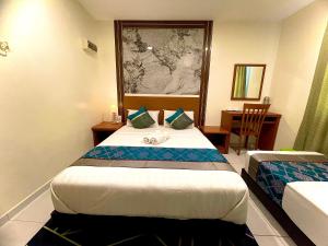 a hotel room with two beds and a table with a chair at Near Jonker Street - JCITYHOTEL - FREE PARKING in Malacca