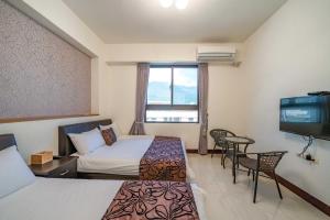 a hotel room with two beds and a flat screen tv at Rain Sun Homestay in Ji'an