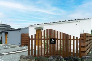 a wooden fence in front of a white house at 軽井沢一棟貸しBBQサウナつき別荘- YURAGI - TSUKI me CHILL in Miyota