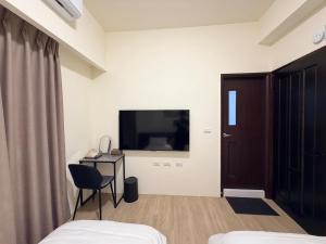 a bedroom with a tv and a desk and a chair at Si Sou Homestay in Nanxi