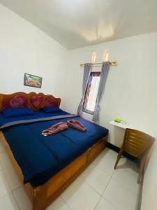 a bedroom with a bed with blue sheets and a chair at Tiba Meka Homestay in Komodo Labuan Bajo Airport