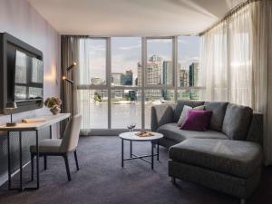 a living room with a couch and a large window at The Sebel Melbourne Docklands Hotel in Melbourne