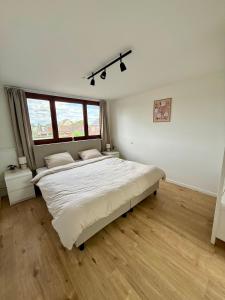 a bedroom with a large white bed with a large window at Het Schuttershof in Hoogstraten