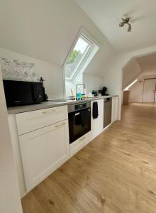 a large kitchen with white cabinets and a window at Het Schuttershof in Hoogstraten