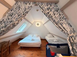 two beds in a attic room with a window at Ets Levillain - Hôtel Les Calètes in Le Tréport
