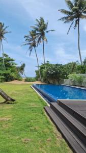 a resort swimming pool with palm trees in the background at Galle Beach Villa in Ratgama Hegoda +15 photos