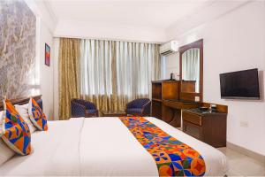 a hotel room with a bed and a desk and a television at FabHotel Golden Emerald in Pune