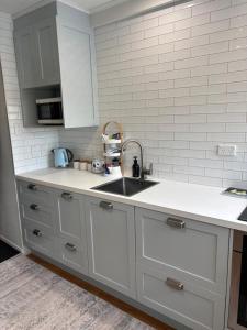 a kitchen with white cabinets and a sink at The Opera View Suite in Oamaru +10 photos
