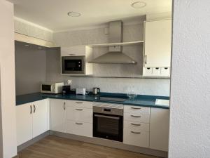 a kitchen with white cabinets and a stove top oven at Apartament Blau Marí in Roses
