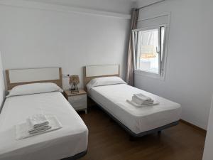 two beds in a small room with a window at Apartament Blau Marí in Roses