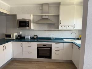 a kitchen with white cabinets and a stove top oven at Apartament Blau Marí in Roses +1 photo