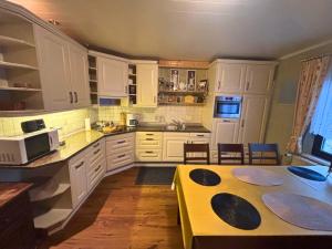 a kitchen with white cabinets and a yellow table at EifelRuhe 2 - Komfortable Ferienunterkunft für bis zu 10 Gäste mit 4 Schlafzimmern, großer Küche und genug Parkplätzen - ideal für Gruppen und Familien, Hunde zulässig in Losheim