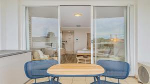 a dining room with a table and chairs and a bedroom at Studio Oasis - Ettalong Beach Resort in Ettalong Beach