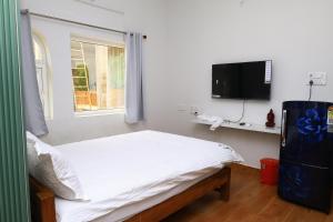 a bedroom with a bed and a flat screen tv at The Aussie House in Mahabalipuram