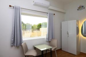 a room with a table and chairs and a window at The Aussie House in Mahabalipuram