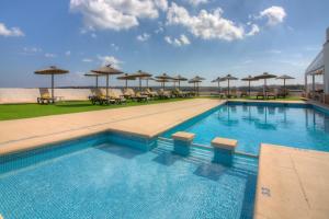 a swimming pool with tables and umbrellas on a building at Hotel Roca Bella in Es Pujols
