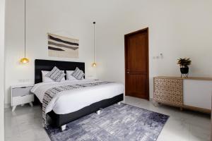 a bedroom with a large bed and a wooden door at KAUH House Canggu in Tumbak Bayuh +13 photos