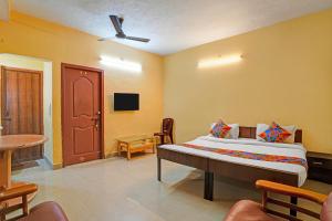 a bedroom with a bed and a table and a door at FabHotel Nimalan Residency Tambaram in Chennai