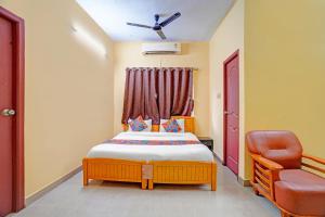 a small bedroom with a bed and a chair at FabHotel Nimalan Residency Tambaram in Chennai