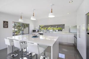 a white kitchen with a white counter and stools at Buena Vista in Gold Coast