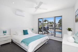 a white bedroom with a bed and a balcony at Buena Vista in Gold Coast