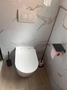a white toilet in a bathroom with two plungers at Refuge de la Basilique in Charleville-Mézières
