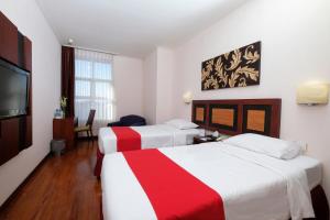 a hotel room with two beds and a flat screen tv at Lampion Hotel Solo in Grogol +3 photos