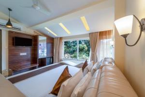 a bedroom with a bed with a couch and a window at Hotel Shanti Solitaire, Arpora in Arpora