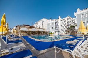 a swimming pool with chairs and umbrellas and buildings at Sunpoint Hotel Bodrum in Bodrum City