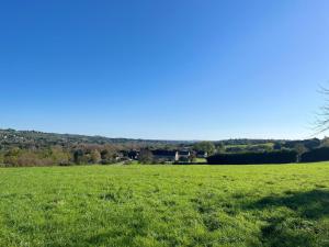 a field of green grass with a house in the distance at Vue sur la colline La-Roche in Bouzais