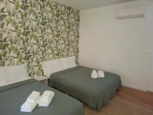 two beds sitting in a room with a wallpaper at Logis Hotel Restaurant Les Platanes in Aramon