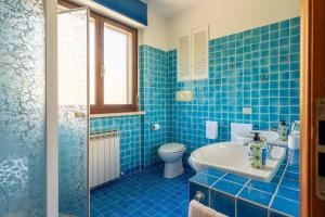 a blue tiled bathroom with a toilet and a sink at Appartamento Posta del Lago in Passignano sul Trasimeno +29 photos