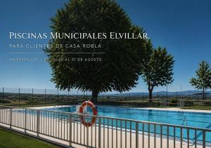 a swimming pool with a fence and a tree at Casa ROBLA in Elvillar