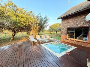 a deck with chairs and a swimming pool at Nghala Self-catering Holiday Home in Marloth Park